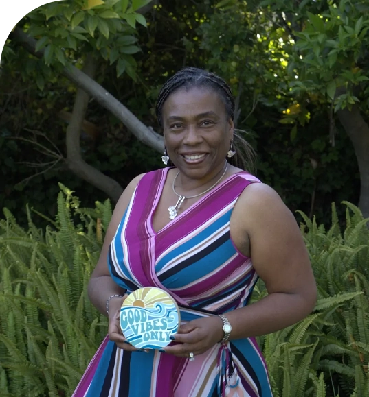 Woman in striped dress holding "Good Vibes Only" sign.